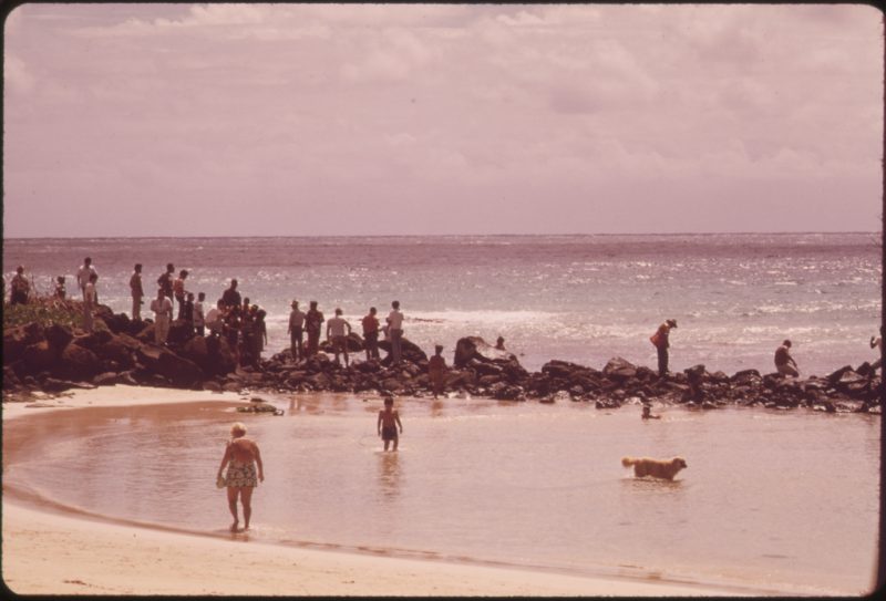 Japanese tourists stand on rocks to watch the Hawaiian fishermen, October 1973