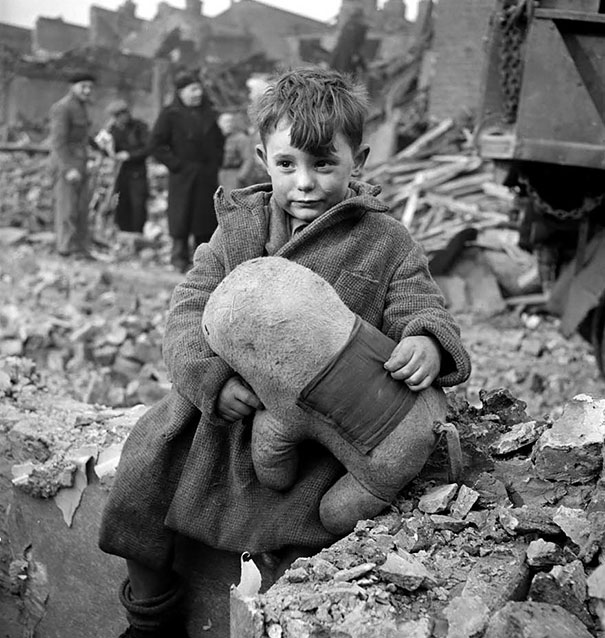 Boy in the ruins with his stuffed animal toy