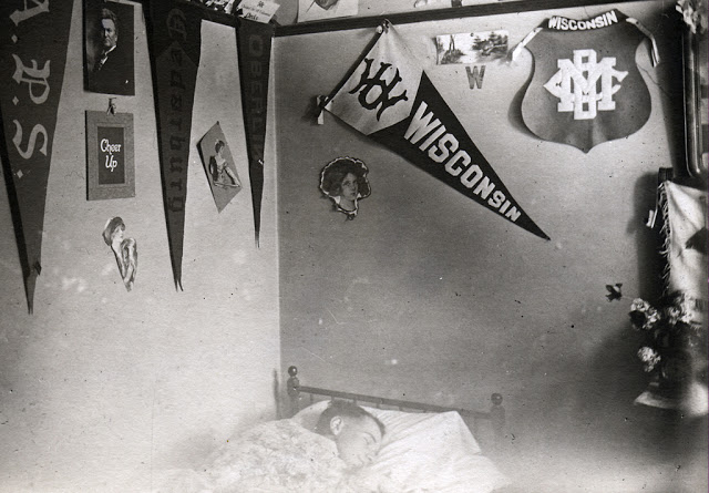 Young student sleeping in a men's boarding house or fraternity house room, ca. 1912.