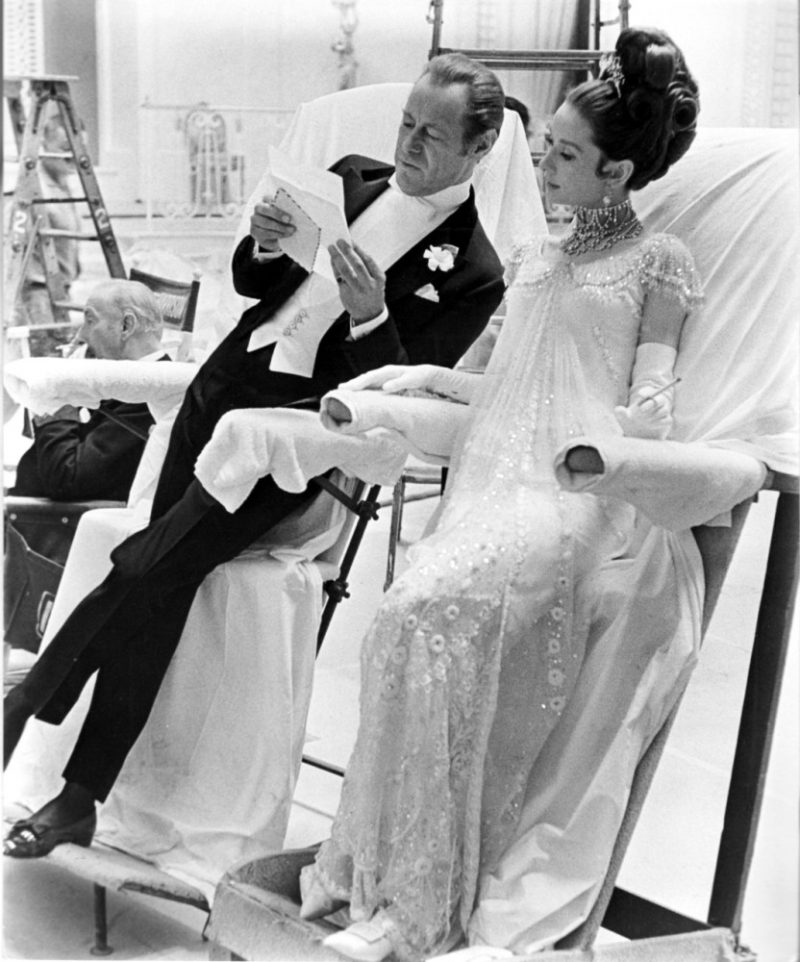 Slant boards keep Rex Harrison and Audrey Hepburn’s elegant attire wrinkle-free during a break on the Burbank set of My Fair Lady (1964).