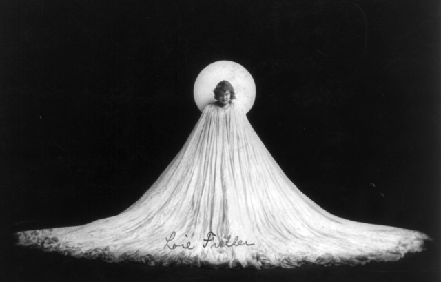 Loie Fuller, full length portrait, art nouveau pose; in elongated white flowing gown Source