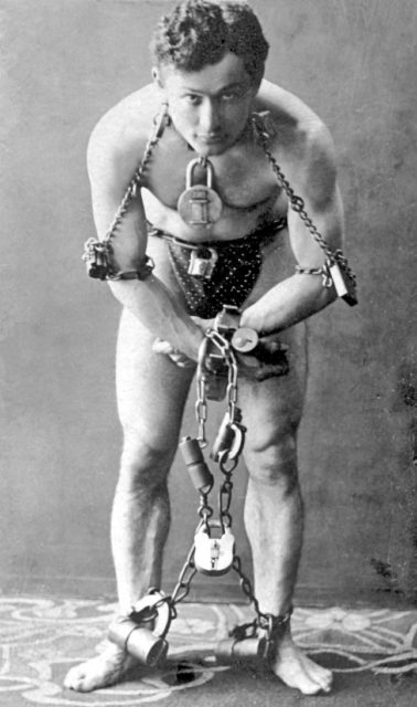Harry Houdini, full-length portrait, standing, facing front, in chains Source