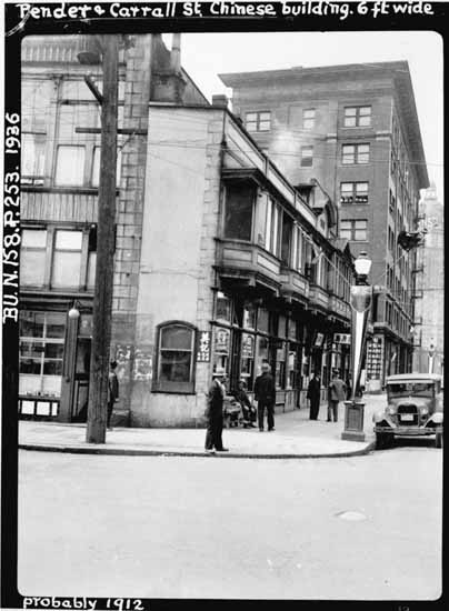 1936 photograph. Central in the photo is the famous Sam Kee building (8 W. Pender St., 1913, extant) with the looming Sang Lung Jan building (26 W. Pender St., 1912-1948) just beyond Shanghai Alley. By Rob/Flickr/Public Domain