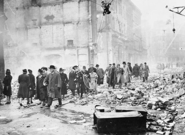 Office workers make their way to work through debris after a heavy air raid.Source