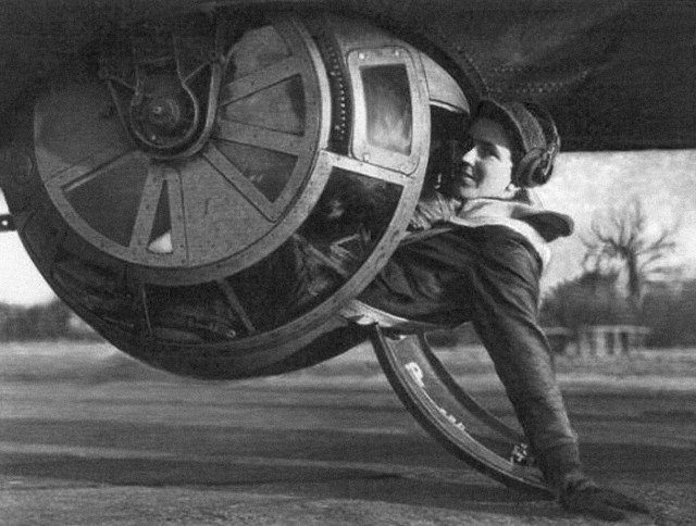 S/Sgt. Alan E. Magee poses for the camera, halfway into the tight confines of the ball turret of a B-17 Flying Fortres