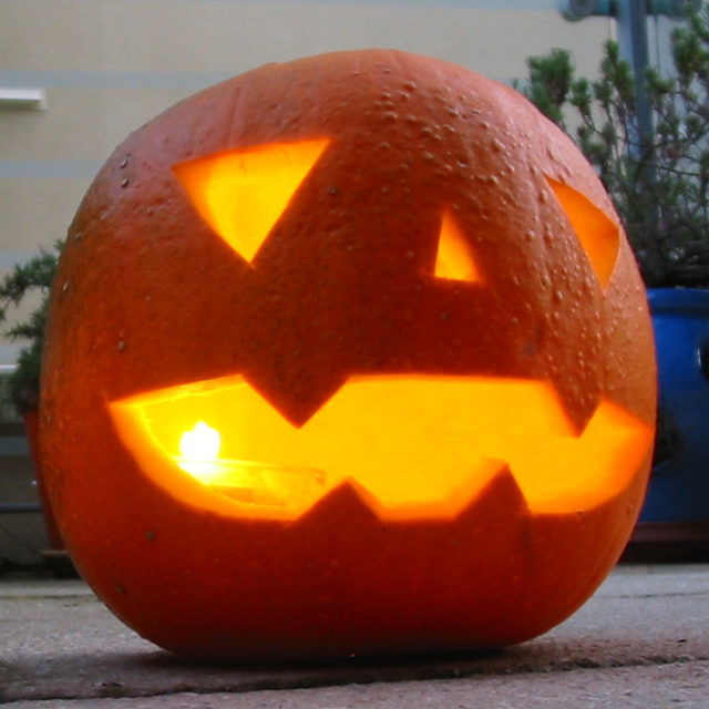 A traditional jack-o'-lantern, made from a pumpkin, lit from within by a candle.