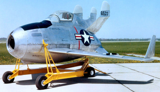 Small egg-shaped aircraft with three vertical stabilizers, resting on yellow movable rig