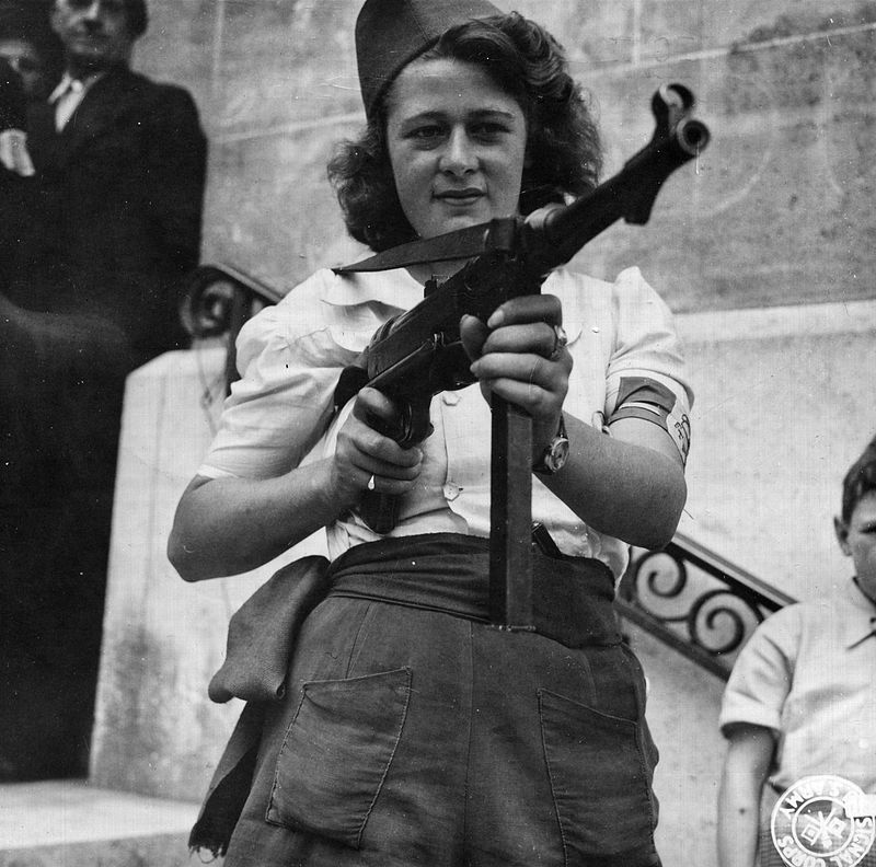 "Nicole", a French Partisan who captured 25 Nazis in the Chartres area, in addition to liquidating others, poses with a German MP 40 with which she is most proficient.