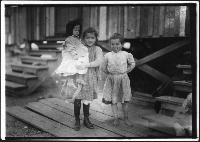 Millie, (about 7 years old) and Mary John (with baby) 8 years old. Both shuck oysters. This is Mary’s second year, February 1911 Photo Credit