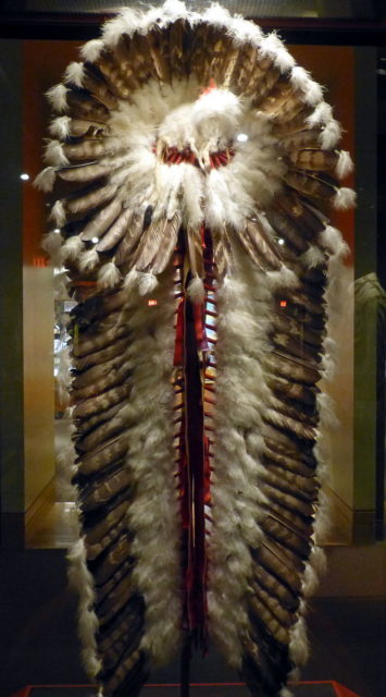National Cowboy & Western Heritage Museum ( Oklahoma City ). Cree trailer headdress ( ca. 1940 ), made of red wool cloth, ribbon, eagle feathers, plume feathers, glass beats, raw hide and felt head Photo Credit 