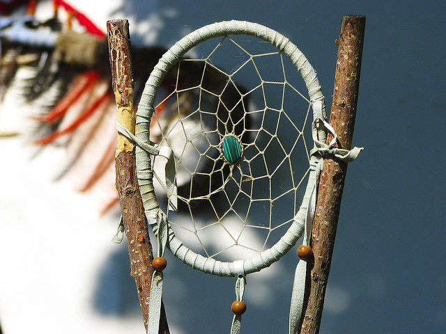 They usually consist of a small wooden hoop covered in a net or web of natural fibers, with meaningful sacred items like feathers and beads attached. Photo Credit