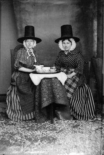 Two women in national dress drinking tea (c. 1875)