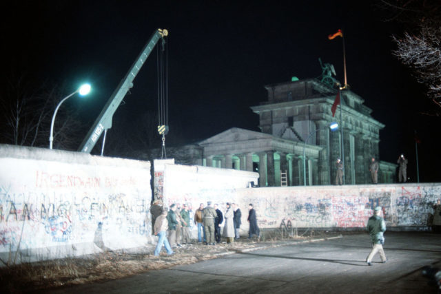 East and West Germans converge at the newly created opening in the Berlin Wall after a crane removed a section of the structure beside the Brandenburg Gate. Photo Credit