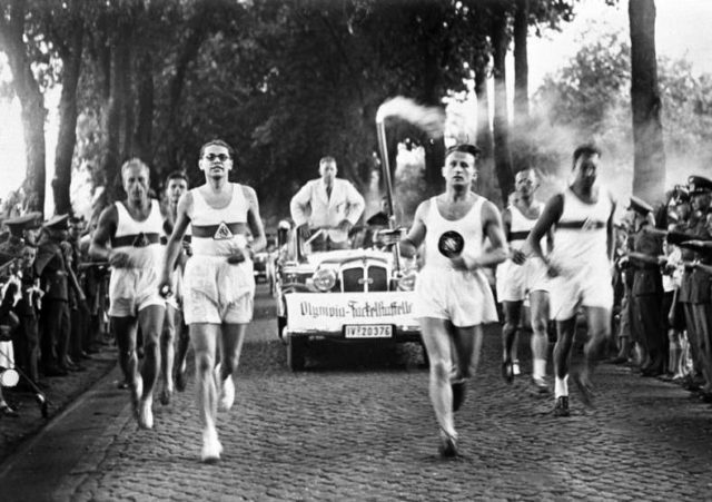 Runners carrying the Olympic Flame Photo Credit