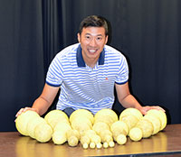 Qin Zhu poses with spheroids he used to study throwing affordances. Some of the spheroids could inflict similar damage as the prehistoric spheroids could to a medium-sized animal. Photo Credit