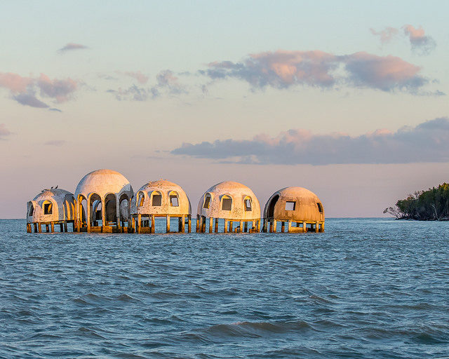 In the 1980s, the Cape Romano Dome House was an ultra-modern dwelling built on a beach on a beautiful island. The forces of nature combined to leave the house standing in the sea, slowly falling apart. This strange sight can be seen near Marco Island, Florida – By Andy Morffew – CC BY 2.0