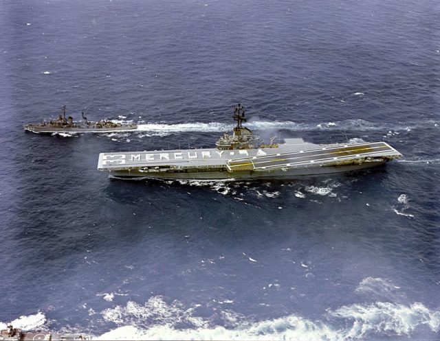 The crew of USS Kearsarge spells out “MERCURY 9” on the flight deck while heading to the recovery area
