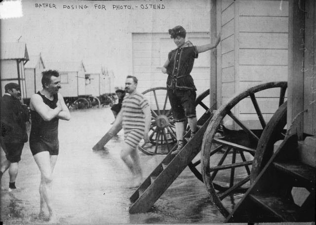Men and women in swimming suits surrounded by Bathing machines