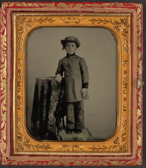 Unidentified young boy in military uniform with “WR” on hat, possibly for Washington Rifles. Photo Credit