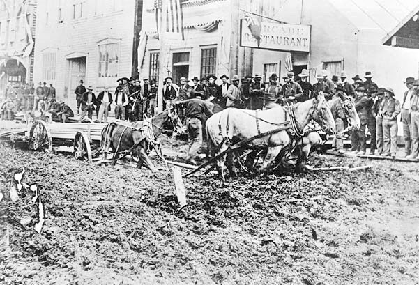 Front Street in Dawson with wagon stuck in mud, 1898