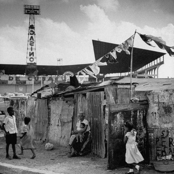 Slum (bohio) dwellings in Havana, Cuba in 1954, just outside Havana baseball stadium. In the background is advertising for a nearby casino