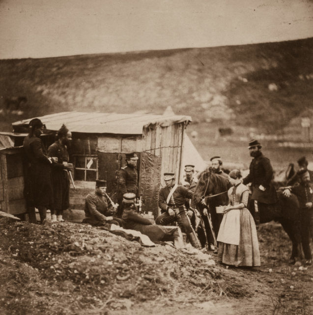 Men of the 4th Dragoon Guards and a woman relax by a hut.