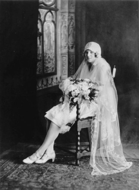Studio portrait of a bride, she wears a cloche hat.