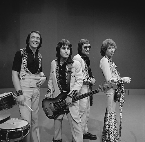 Examples of Teddy Boy-style clothing worn by Ray Stiles and Les Gray of ’70s glam rock band Mud: drape jackets, brothel creepers and drainpipe trousers. Author:AVRO – Beeld En Geluid Wiki – Gallerie: Toppop 1974 CC BY-SA 3.0
