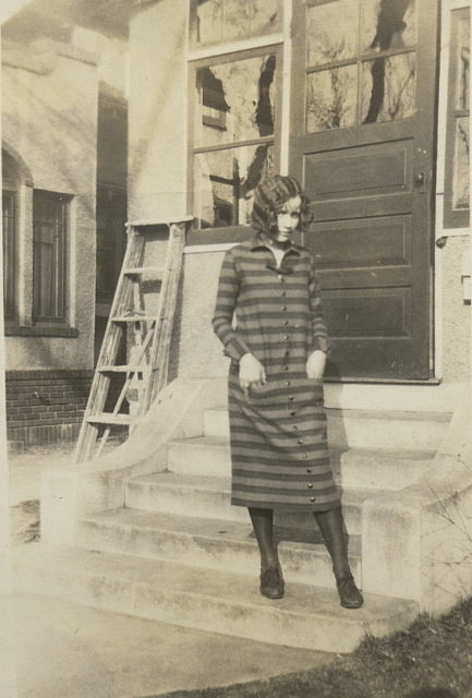 Young woman standing in a casual, striped dress, exterior, 1925.