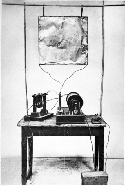 Marconi’s first transmitter incorporating a monopole antenna. It consisted of an elevated copper sheet (top) connected to a Righi spark gap (left) powered by an induction coil (center) with a telegraph key (right) to switch it on and off to spell out text messages in Morse code.