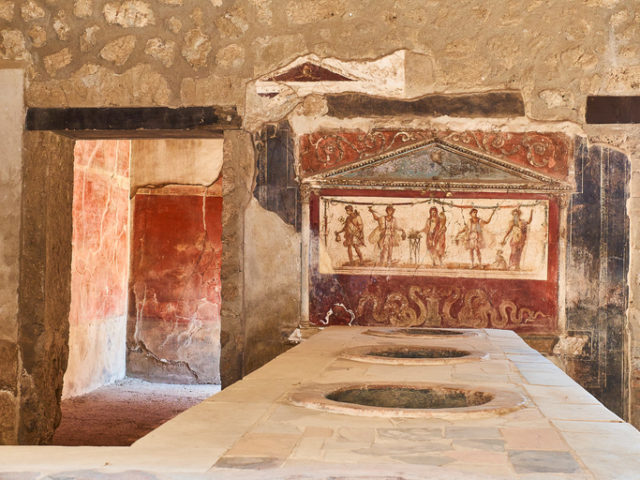 Dolias and fresco detail, of archaeological remains of Thermopolium of Vetutius Placidus, at Ruins of Pompeii. The city was an ancient Roman city destroyed by volcano Vesuvius. Pompeii, Campania, Italy.