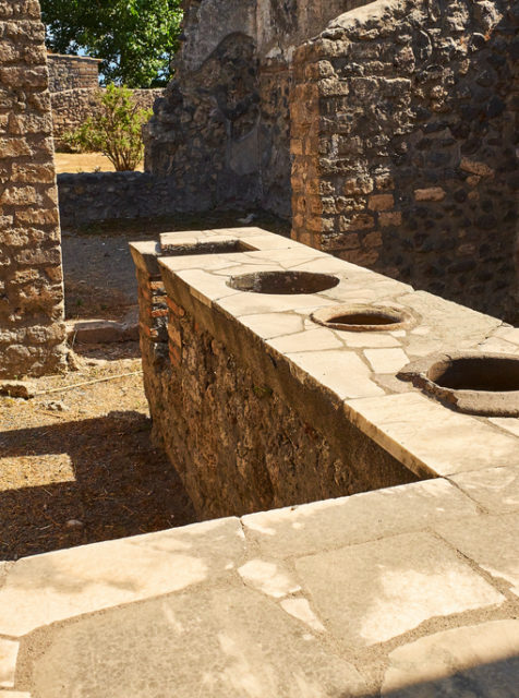 Thermopolium of archaeological remains of Via della Abbondanza street at Ruins of Pompeii. The city was an ancient Roman city destroyed by the volcano Vesuvius. Pompei, Campania, Italy.