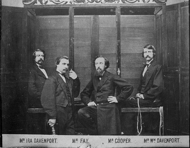 Photograph of the Davenport Brothers in front of their spirit cabinet