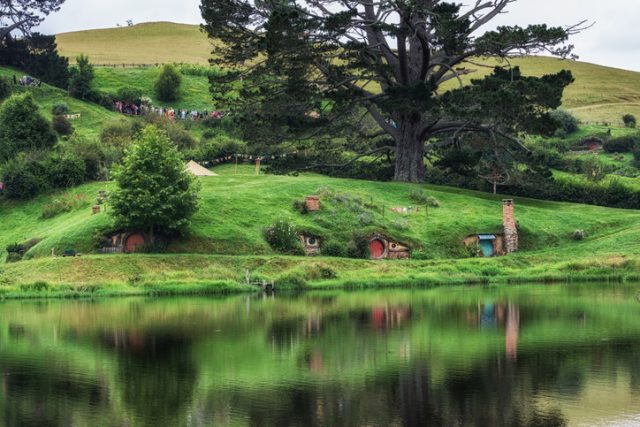 hobbit holes in Hobbiton movie set reflecting in a small lake. Taken in New Zealand.