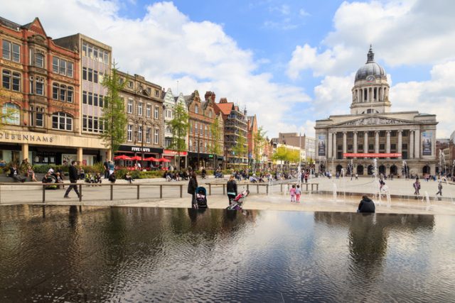 Nottingham, England – May 17, 2016: Various people sitting, walking, visiting in the main Market Square, Nottingham Council House building behind.