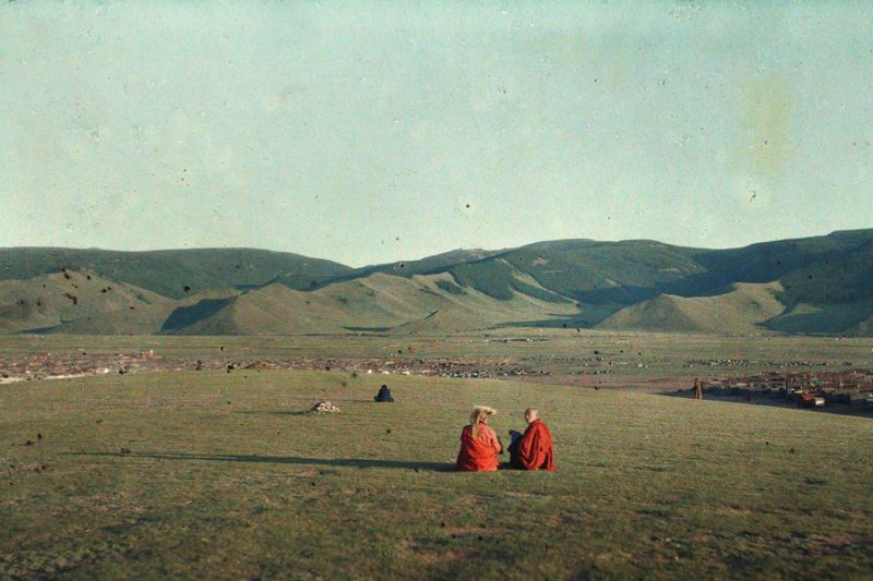 Two monks sit in the open plains outside the capital