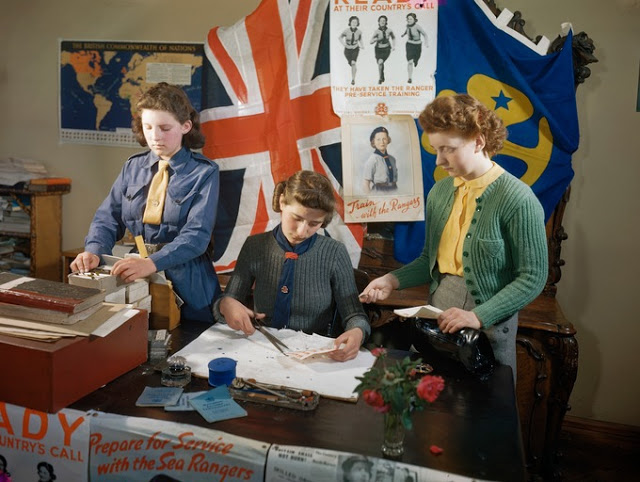 A girl guide and a sea ranger selling saving stamps as part of the War Effort.