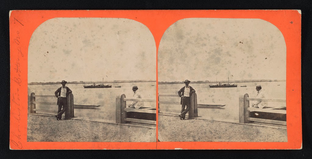 A view of Charleston harbor from the battery with a ship at anchor in the distance. One man leans against the fence post while another is seated on a bench., 1861
