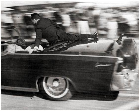 Secret Service Special Agent Clint Hill shields the occupants of the Presidential limousine moments after the fatal shots.