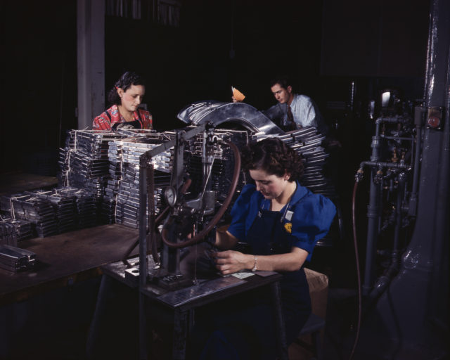 Workers feed sections of sheet metal through a pneumatic numbering machine at the North American Aviation plant in Inglewood, California.