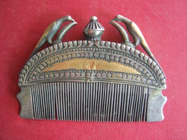 Indian metal comb for keeping hair in place, adorned with a pair of birds. After removing the central stopper, perfume can be poured into the opening in order to moisten the teeth of the comb and the hair of the wearer.Source 