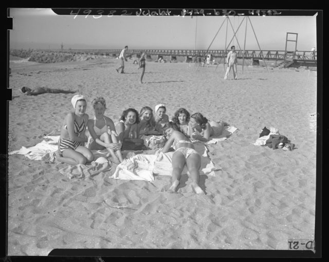 Eight girls laying in the sand while tanning with jetty in the background at Cabrillo Beach, Calif., 1947 .source