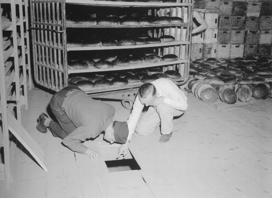 A US Army lieutenant and a German police officer investigate the floorboards of the bakery in which the poison was hidden. Source: Public Domain, US National Archive