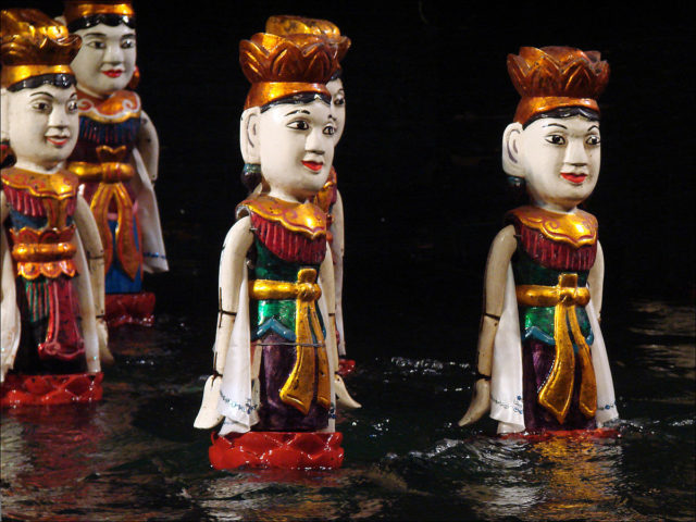The puppets enter from either side of the stage, or emerge from the murky depths of the water. Source