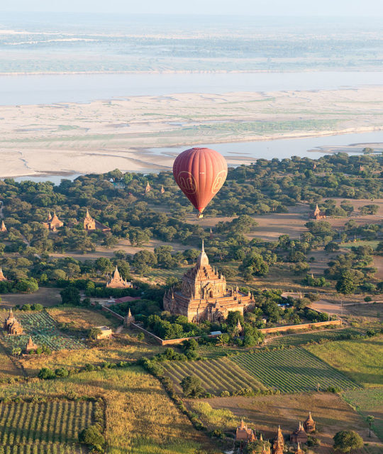 A hot-air balloon flying over a pagoda in Bagan Photo Credit