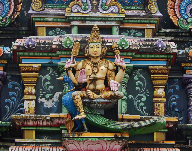 A sculpted depiction of Lord Murugan stands over the central temple. Photo Credit