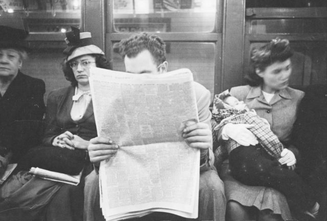 Passenger reading a newspaper in a subway car Photo Credit