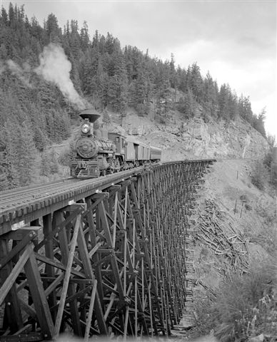 In all cases, the curvature of the rail line was minimized through long graceful curves across several trestles, and by turning the rail line gradually throughout the length of the longer trestles. The largest of the wood frame trestles, the trestle at Mile 87.9 crossing the West Canyon Creek, was a stupendous structure, 750′ long and 182′ high, and turned the rail line almost 90 degrees over its entire length at the head of the canyon