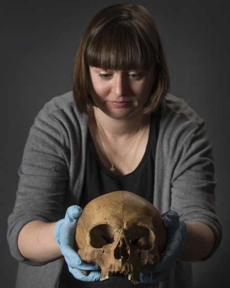 Dr. Rebecca Redfern holds a Roman skull that was tested for the Written in Bone exhibition.