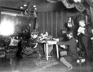 Table levitates during Palladino's séance at home of astronomer Camille Flammarion, France, 25 November 1898. There are two women seated at the table. Palladino sits at the far short end